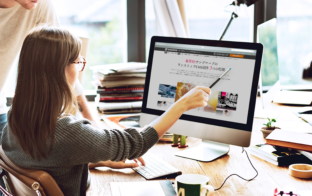 デスクトップパソコンでWEBサイトを確認している男女の画像