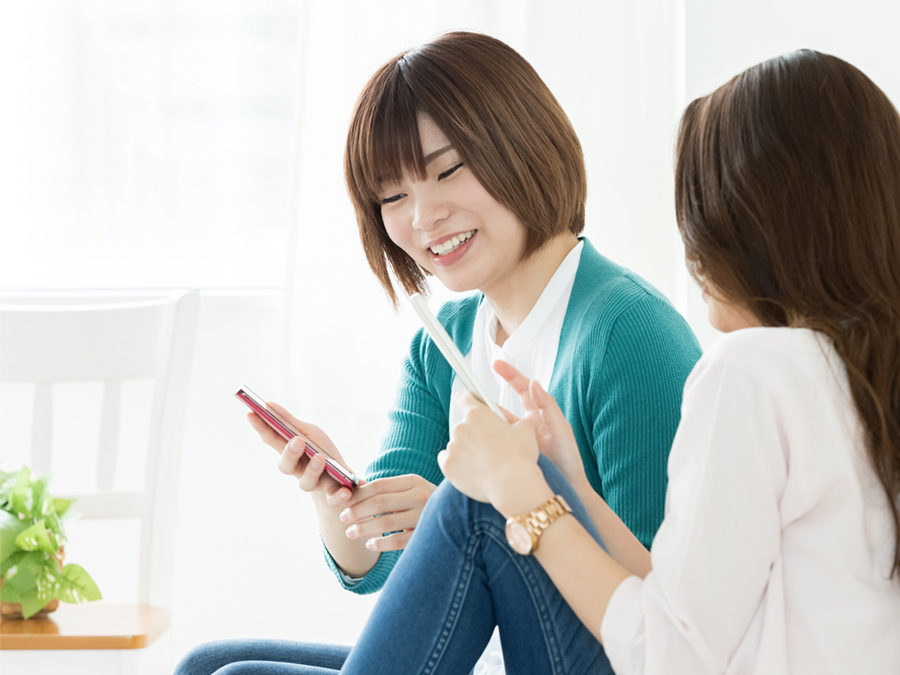 スマートフォンを見ながら情報を交換している女性たち